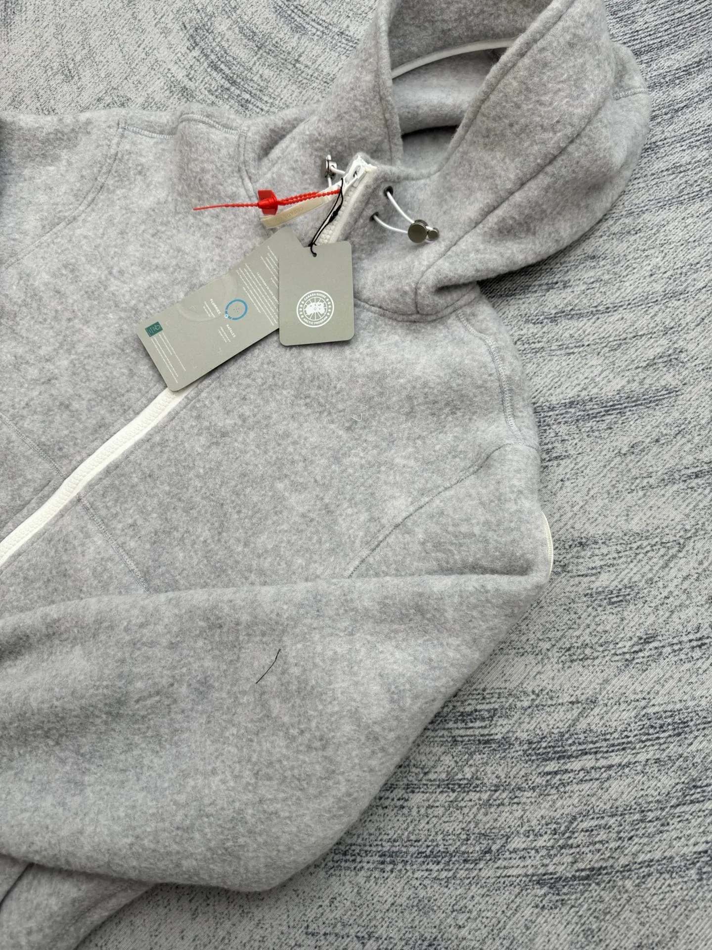 P810 Canada Goos Fleece Badge Hooded Jacket SIZE S/M/L/XL The fabric is made of wool as the main body, with a very small amount of spandex and polyester fiber blended into the wool fleece fabric. The sleeves and hem are closed with 2×2 ribbing. Its strong elasticity can closely fit wrists and waists of different thicknesses, forming an effective 'seal' to prevent cold wind from blowing back. It can still maintain its original shape after repeated stretching and use, and is not easy to loose and deform. And the ribbed cuffs can convey a sense of design and enhance the visual beauty.
